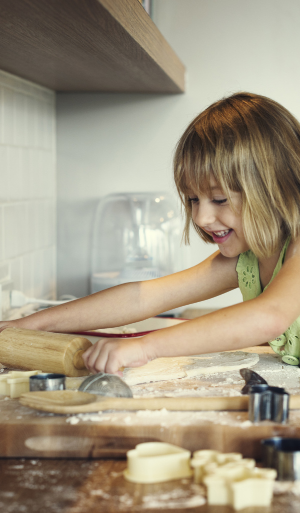 Маленькая девочка на кухне готовит печенье