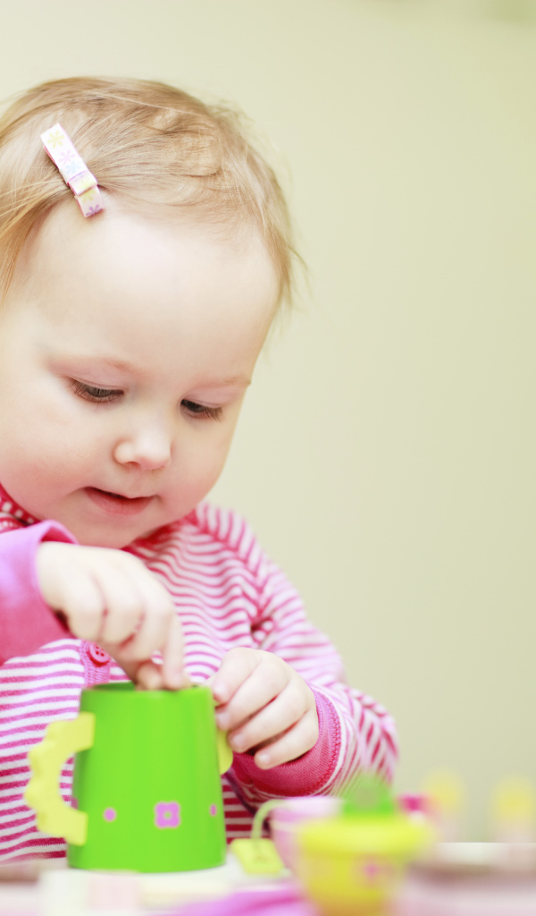 Маленькая девочка играет с посудой 