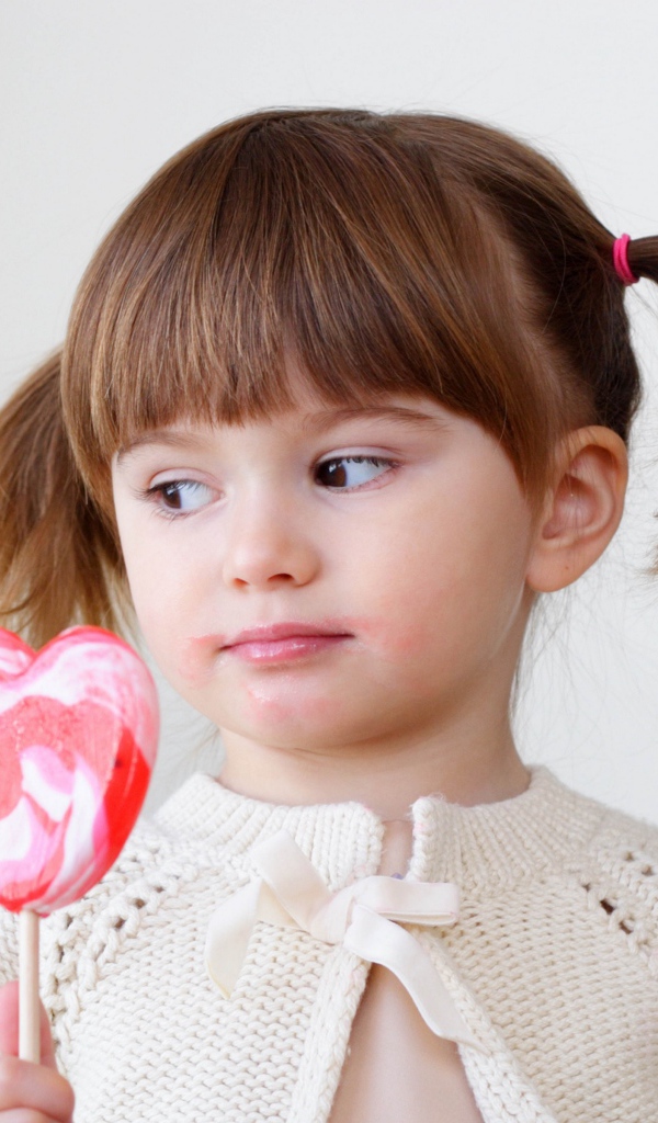 Маленькая девочка с большой конфетой на палочке