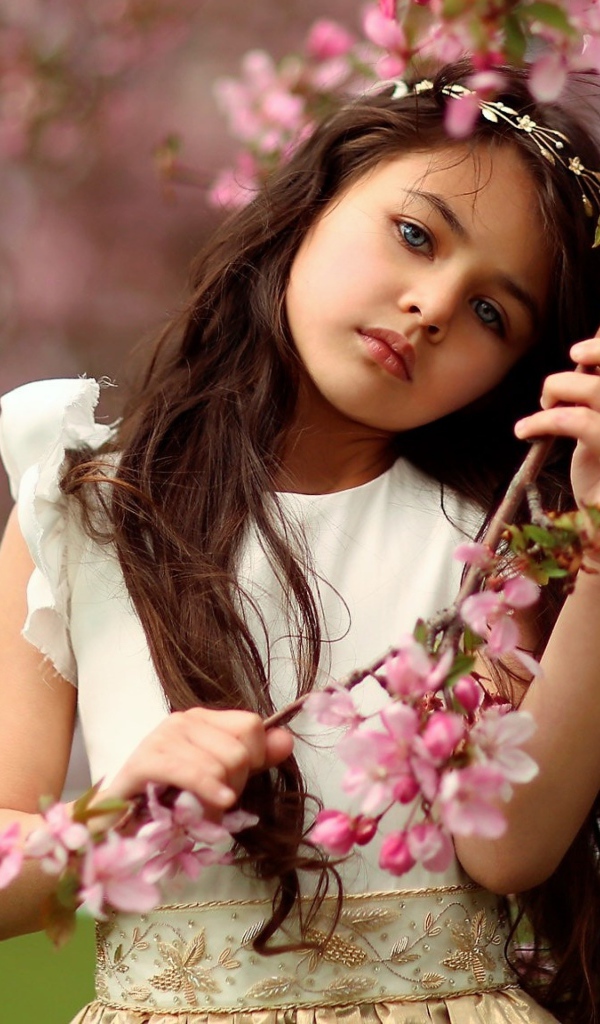 Маленькая девочка у цветущей розовыми цветами ветки