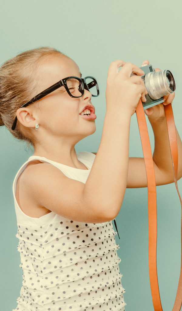 Маленькая девочка в очках с фотоаппаратом