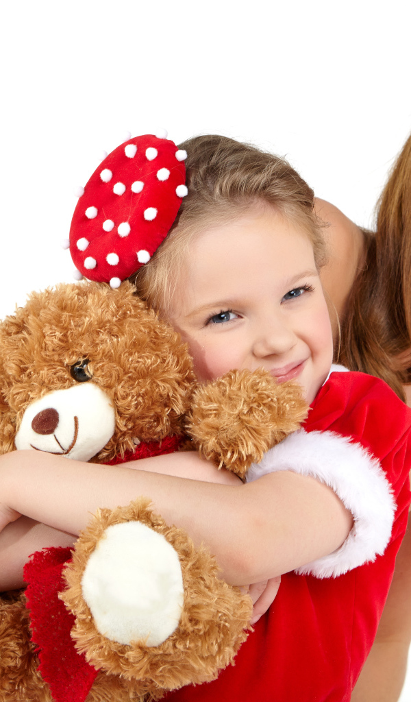 Маленькая девочка с мамой обнимает игрушечного медвежонка