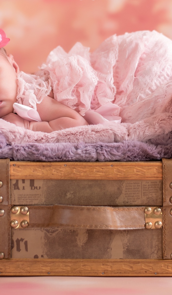 Маленькая новорожденная девочка спит на чемодане