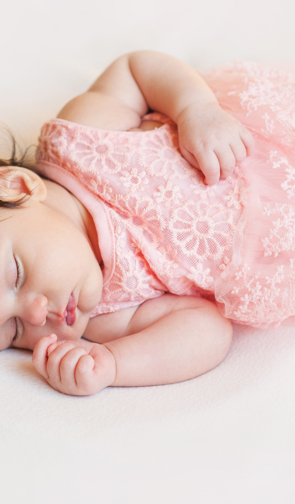 Маленькая спящая девочка в розовом платье с цветком в волосах 