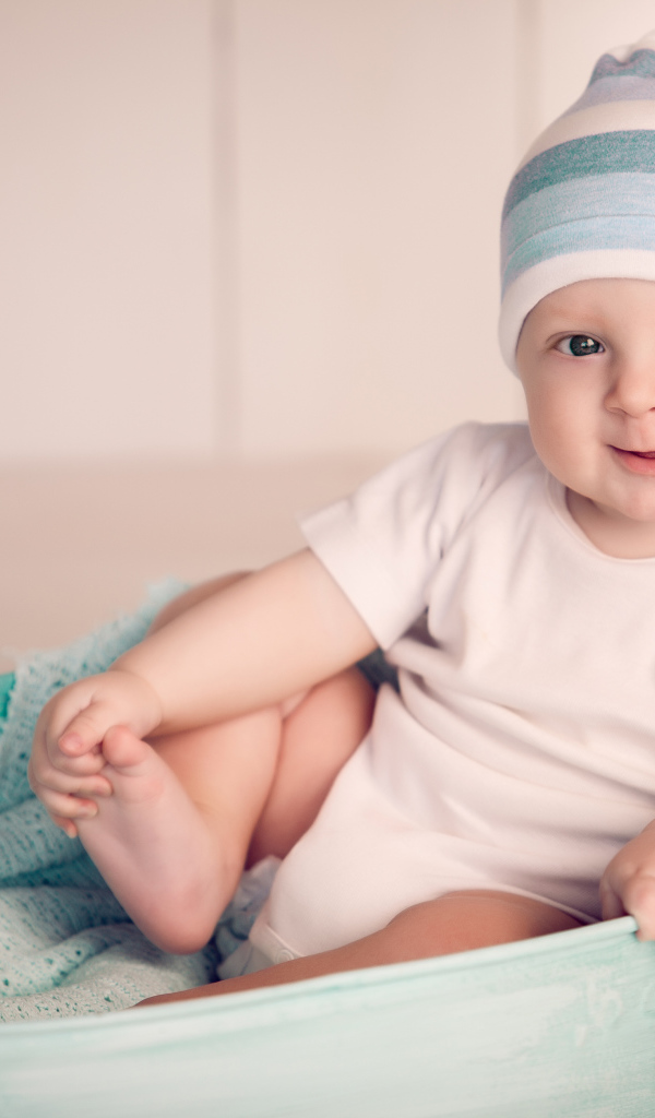 Маленький улыбающийся ребенок сидит в железном тазике