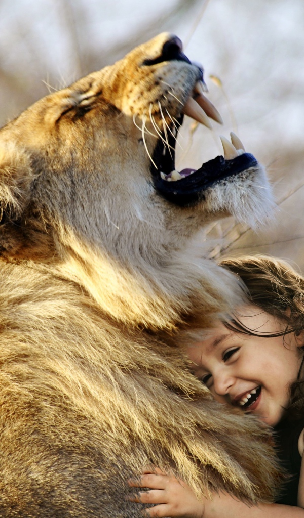 Маленькая улыбающаяся девочка обнимает льва
