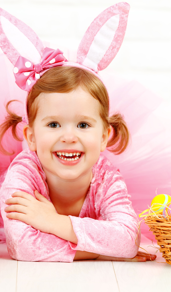 Маленькая улыбающаяся девочка в розовом с пасхальными яйцами и букетом тюльпанов