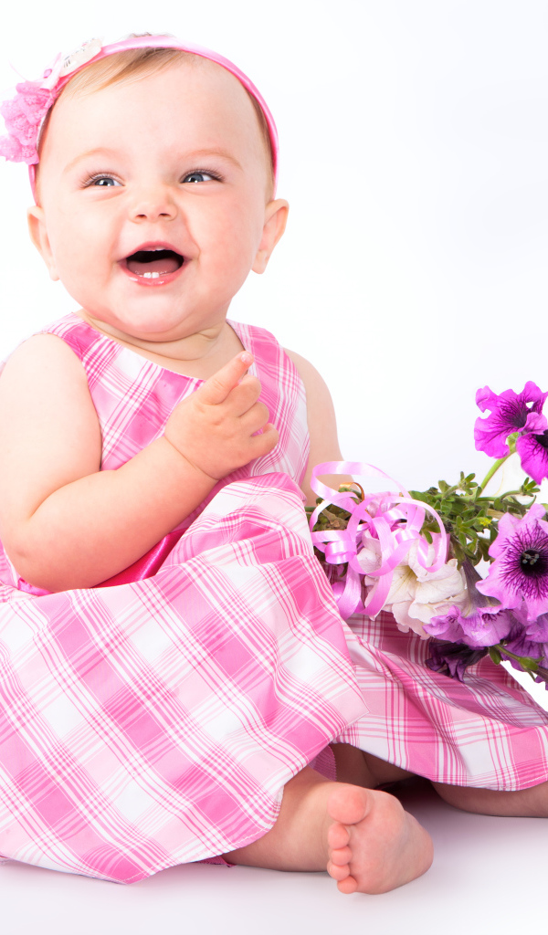 Маленькая улыбающаяся девочка с букетом петунии на белом фоне