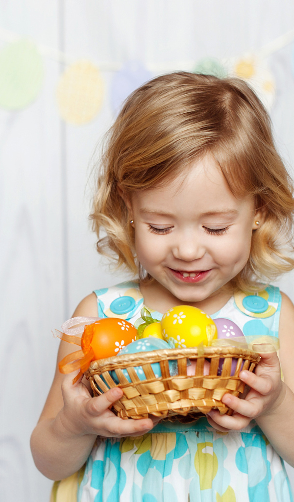 Маленькая улыбающаяся девочка с пасхальными яйцами в руках