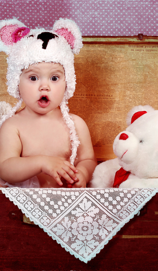 Маленький удивленный ребенок сидит в чемодане с игрушками