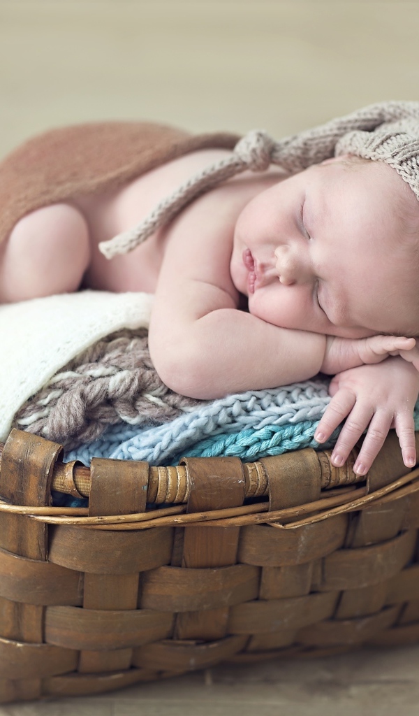 Спящий грудной ребенок в шапке в корзине 