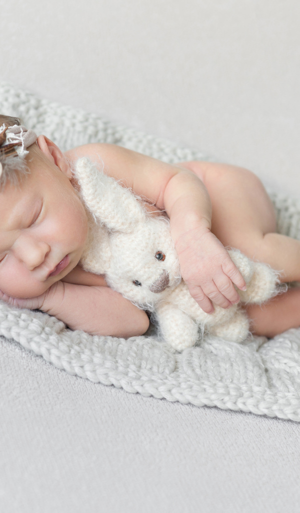 Спящий младенец с игрушкой на сером фоне 