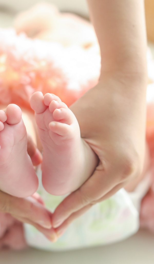 Маленькие ножки новорожденного в ладонях у мамы 