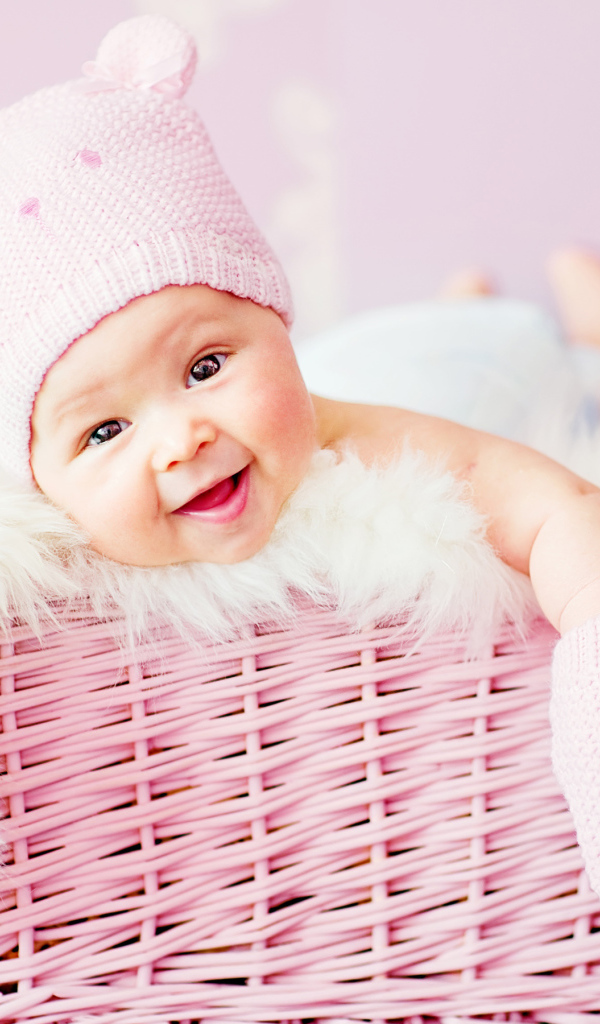 Улыбающийся грудной ребенок лежит в розовой корзине