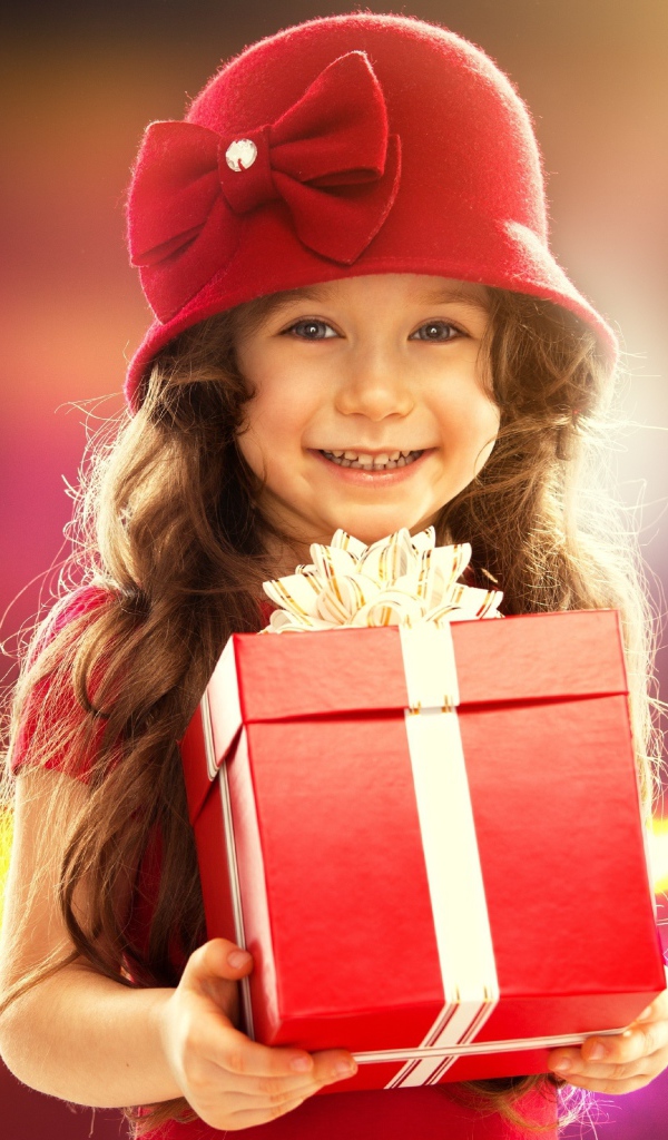 Улыбающаяся голубоглазая девочка с большим подарком в руках