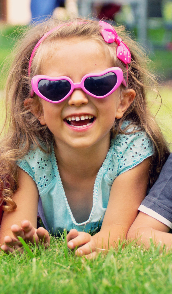 Улыбающиеся мальчики и девочка лежат на зеленой траве