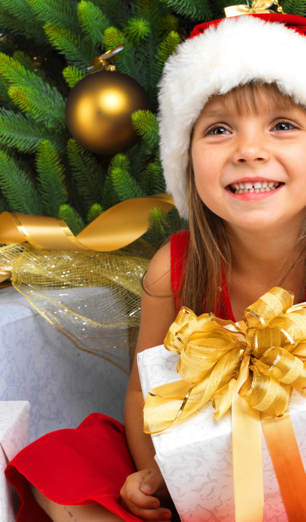 Улыбающаяся девочка в новогоднем костюме с подарками под елкой