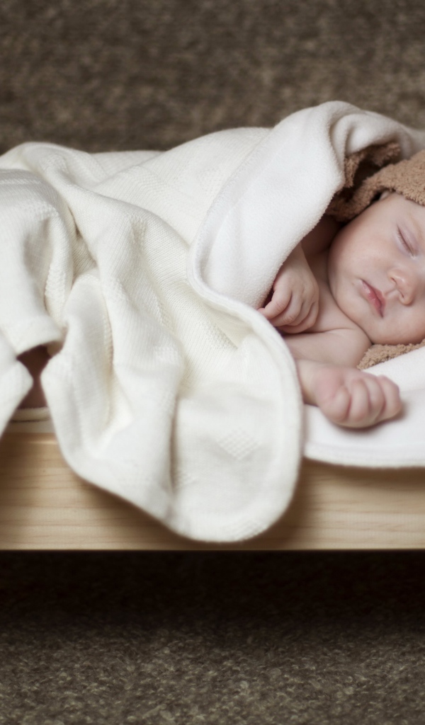 Грудной ребенок спит в маленькой кроватке