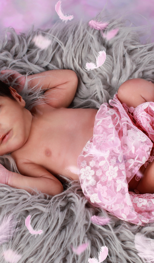 Младенец лежит на сером меховом покрывале 