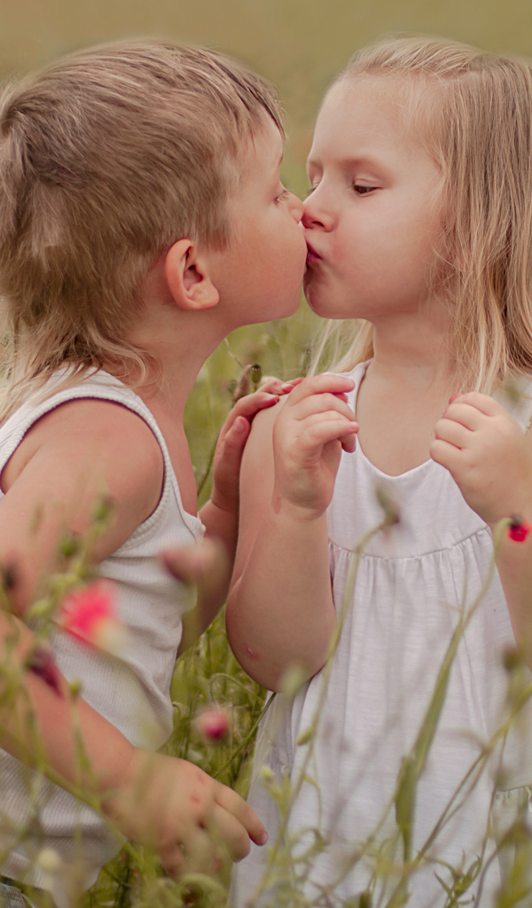 Первый поцелуй мальчика и девочки на цветущем поле