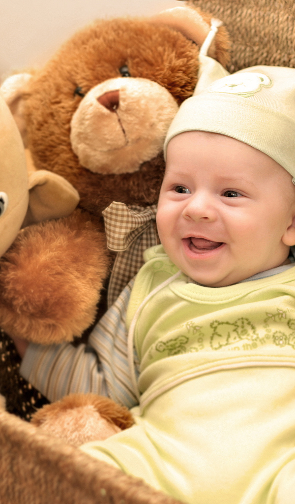 Грудной улыбающийся ребенок в корзине с игрушками