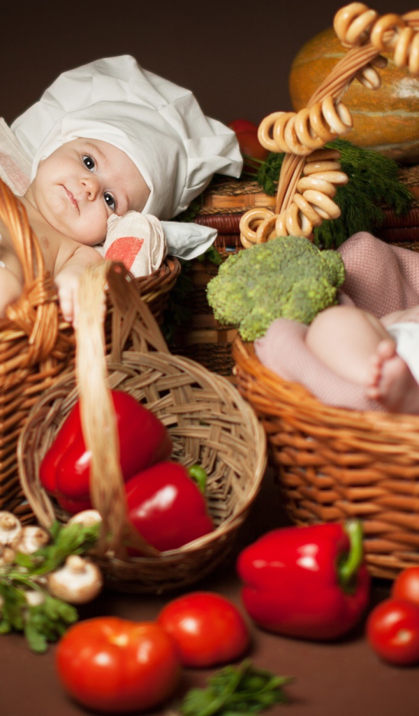 Два младенца в шапках повара лежат в корзинах с продуктами