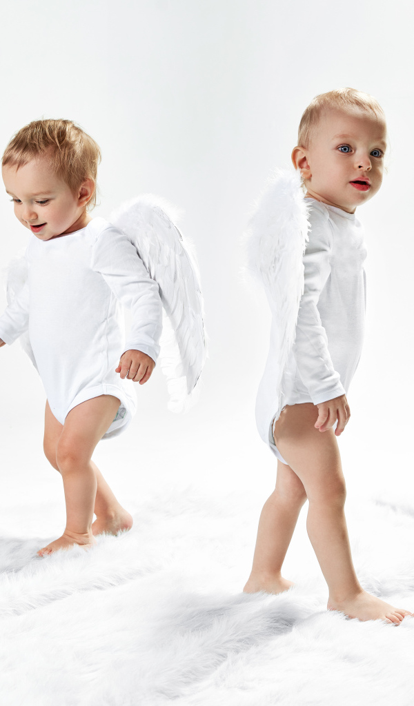 Два маленьких мальчика в костюмах ангела на белом фоне