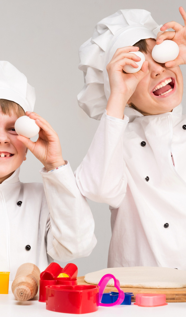 Два маленьких мальчиках в костюмах повара на кухне
