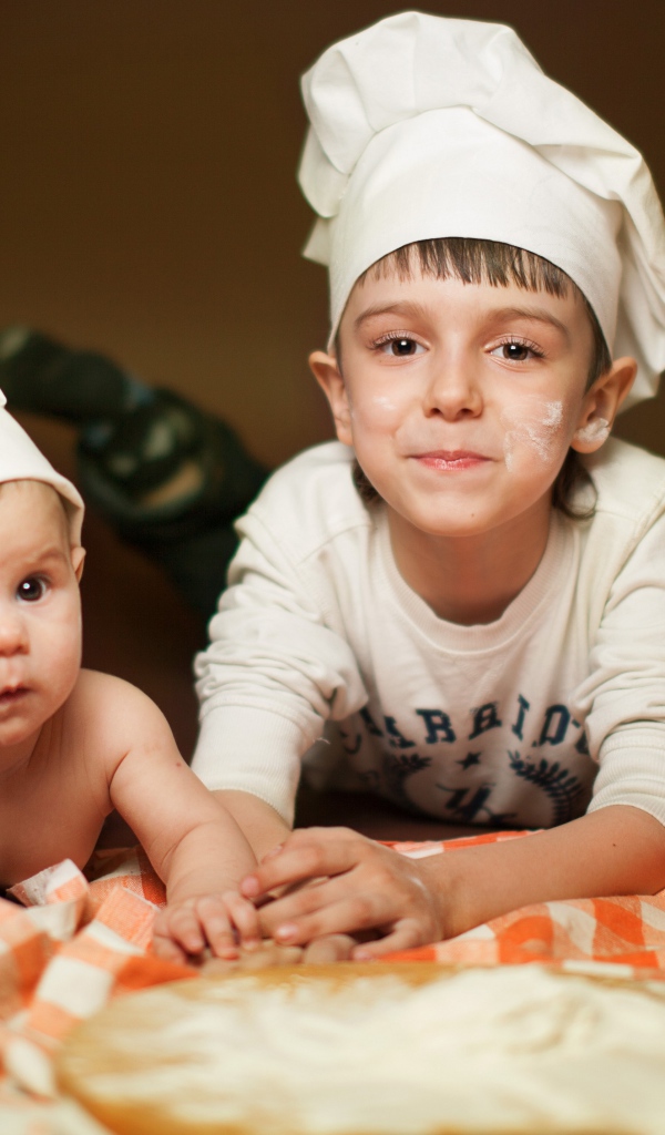 Два маленьких мальчика в шапках повара на кухне