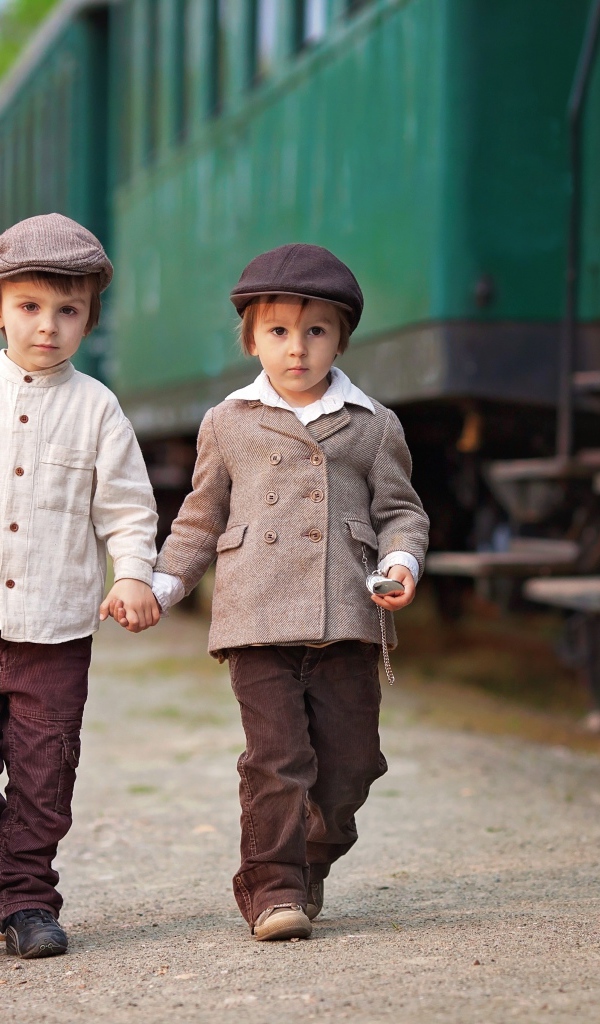 Два маленьких мальчика с большим чемоданом у поезда