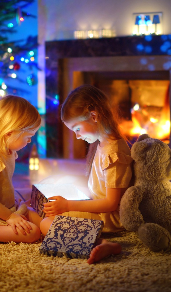 Две маленькие девочки с игрушками у камина