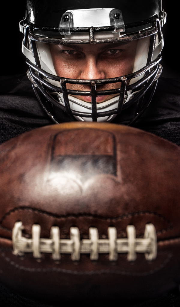 Американский футболист с мячом на черном фоне