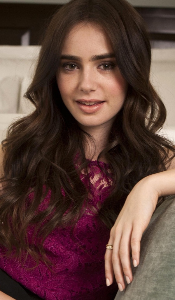 Красивая брюнетка, актриса Лили Коллинз сидит на диване