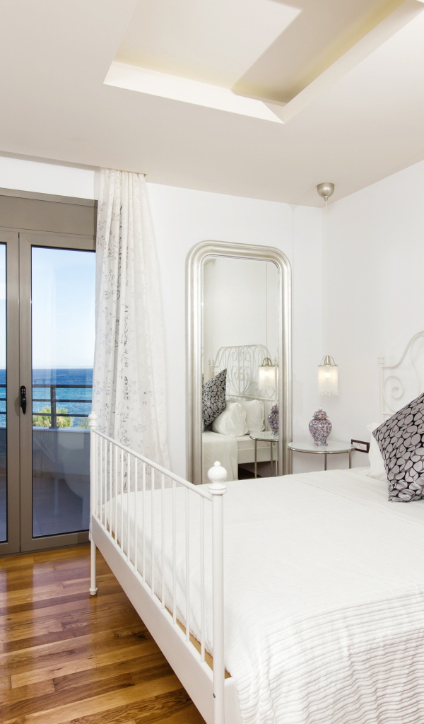 Светлая спальня с большой белой кроватью и телевизором 