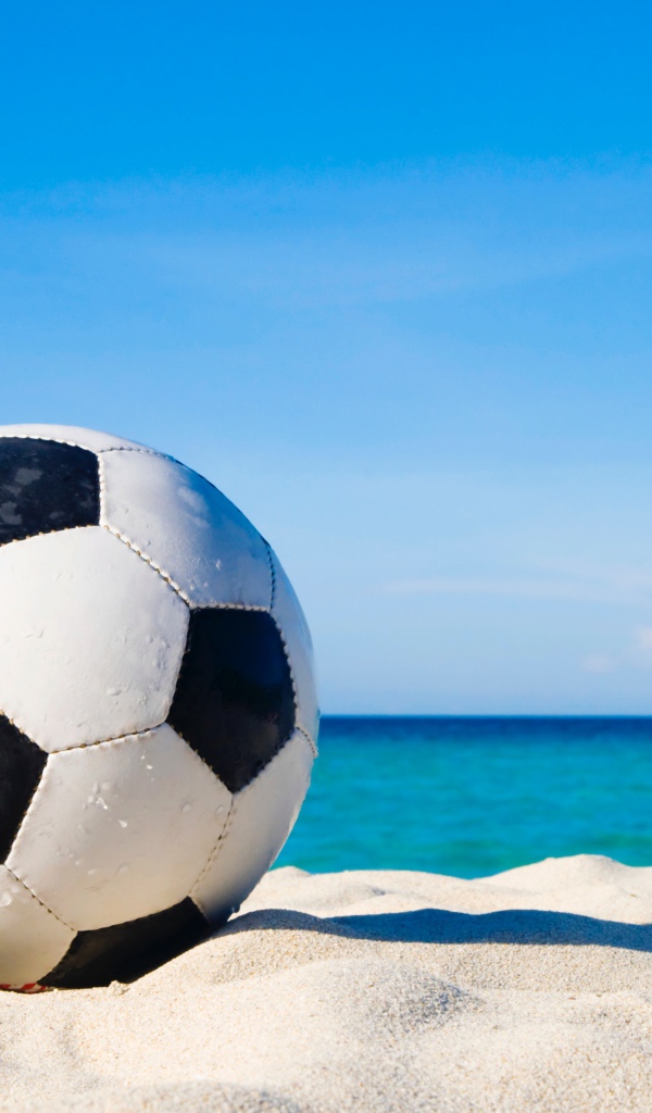 Футбольный мяч на белом песке на фоне голубого неба