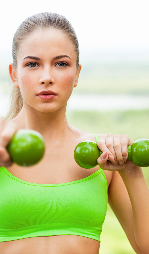 Молодая спортивная блондинка с гантелями в руках