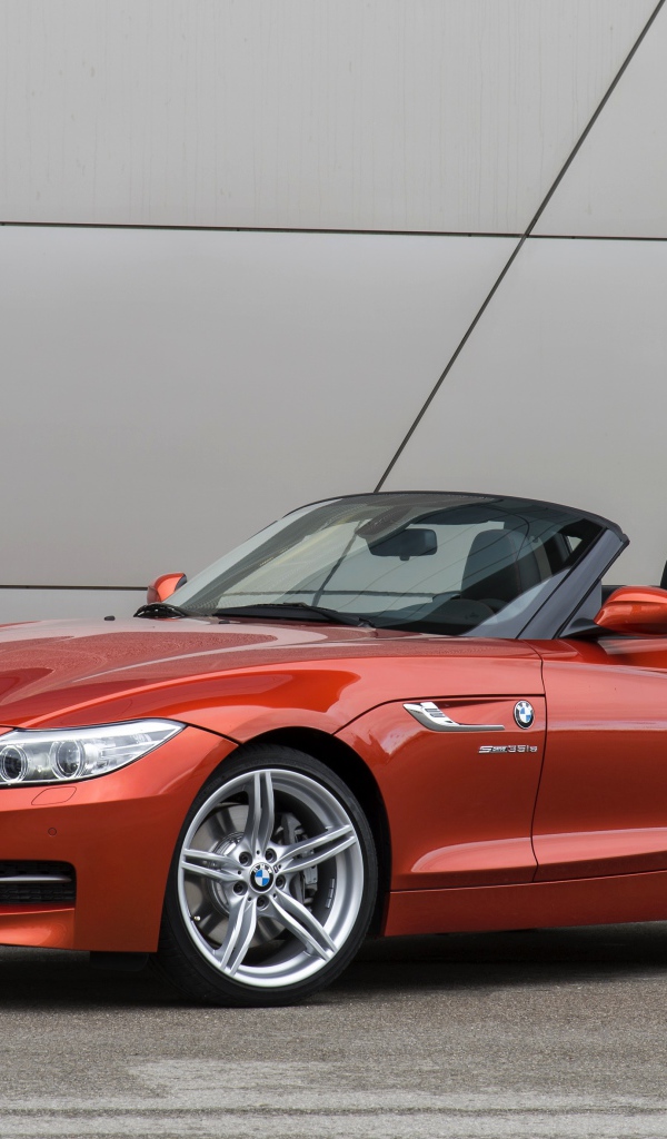 Оранжевый автомобиль кабриолет BMW Z4 на фоне стены
