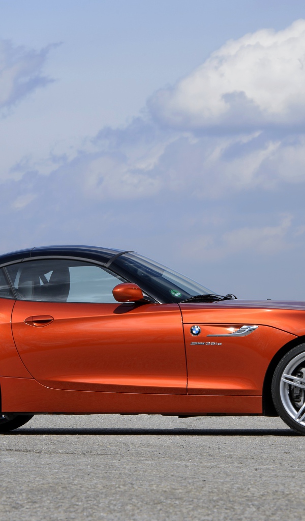 Оранжевый автомобиль BMW Z4 на фоне красивого неба