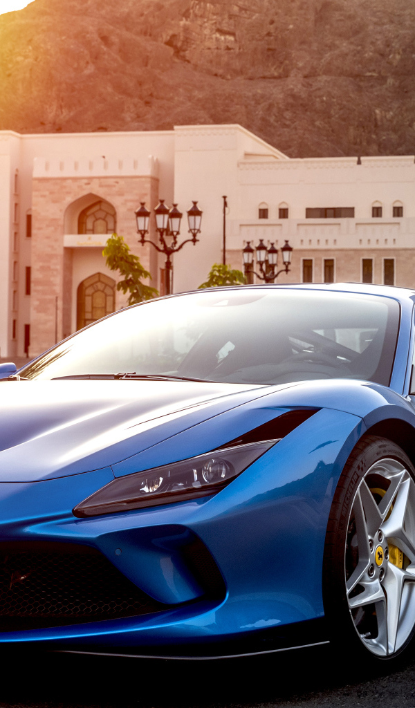 Голубой спортивный автомобиль Ferrari F8 Tributo 2019 года на фоне здания