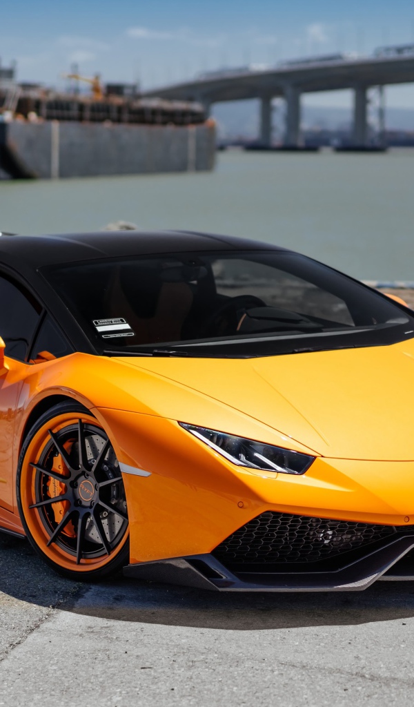 Оранжевый быстрый Lamborghini Huracan в порту у воды
