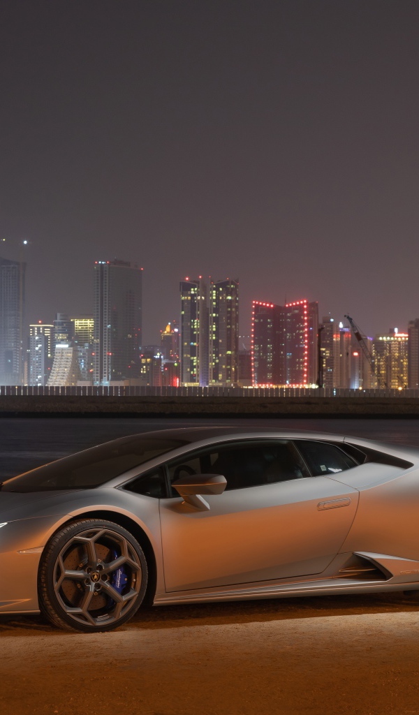 Серебристый автомобиль Lamborghini Huracan Evo на фоне города