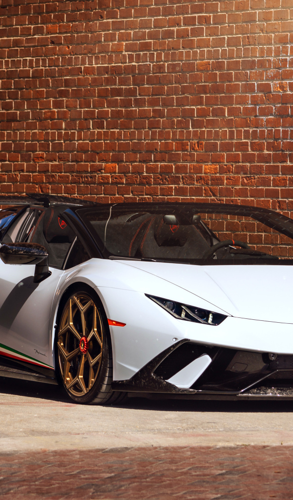 Белый быстрый Lamborghini Huracan стоит у кирпичной стены