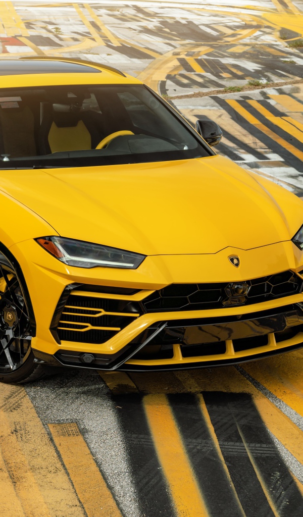 Желтый внедорожник Lamborghini Urus на разноцветном асфальте 