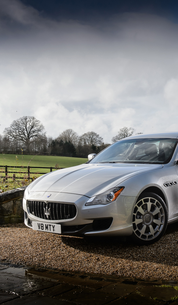 Серебристый стильный дорогой автомобиль Maserati Quattroporte на дороге после дождя