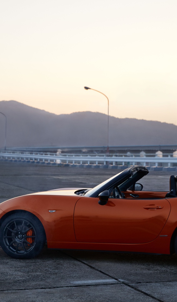 Оранжевый автомобиль кабриолет Mazda MX-5 на фоне неба