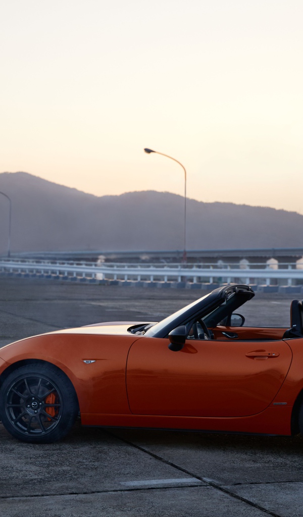 Оранжевый автомобиль кабриолет Mazda MX-5 на фоне неба