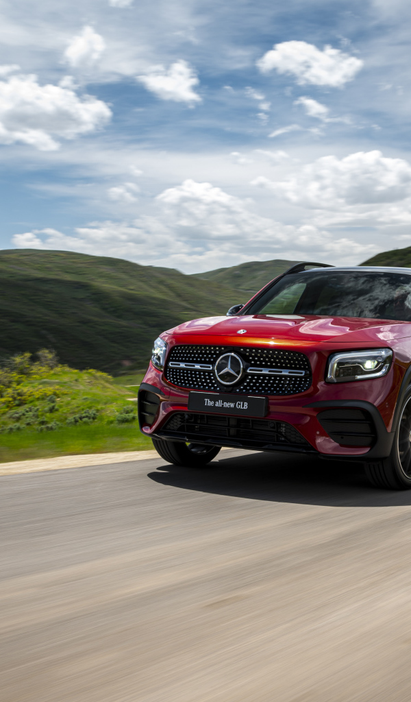Красный автомобиль Mercedes-Benz GLB-Class  на фоне зеленых холмов