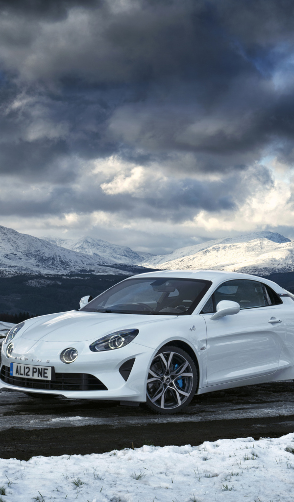 White car Alpine A110 on a background of mountains under a stormy sky