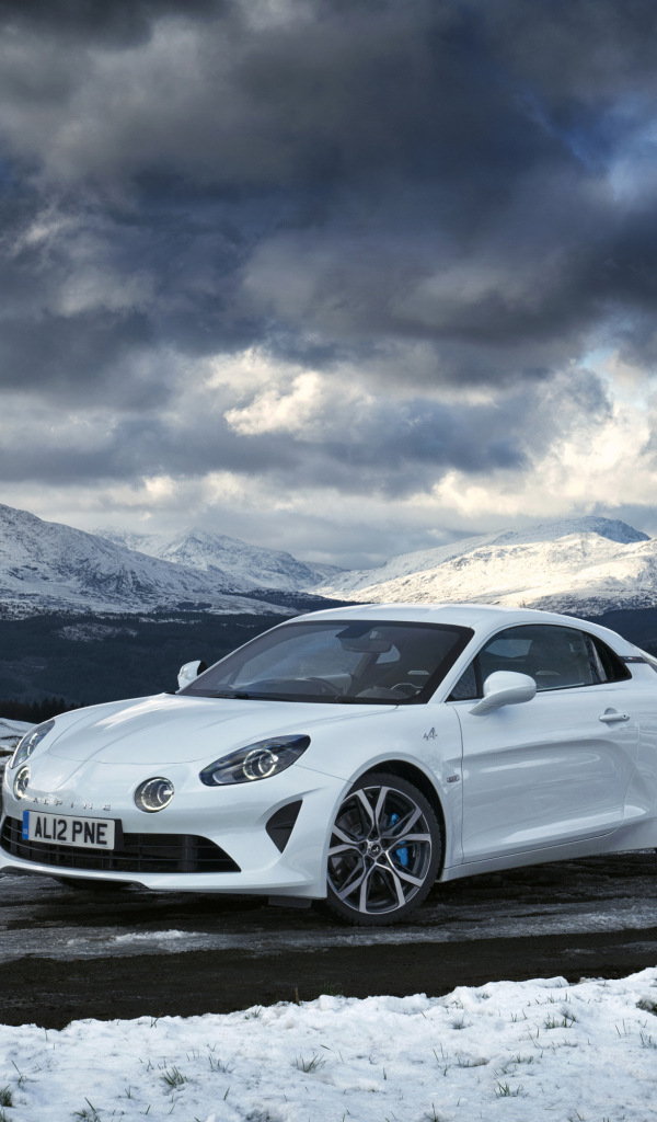 Белый автомобиль Alpine A110 на фоне гор под грозовым небом  