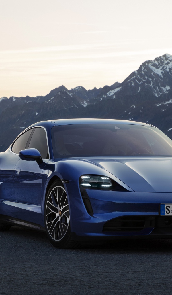 Синий стильный автомобиль Porsche Taycan Turbo 2019 года на фоне гор